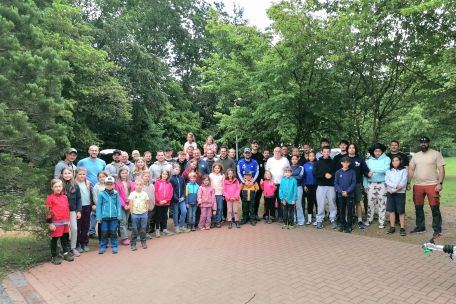 etwa 70 Kinder, Jugendliche, Väter und Großväter stehen im Halbkreis
