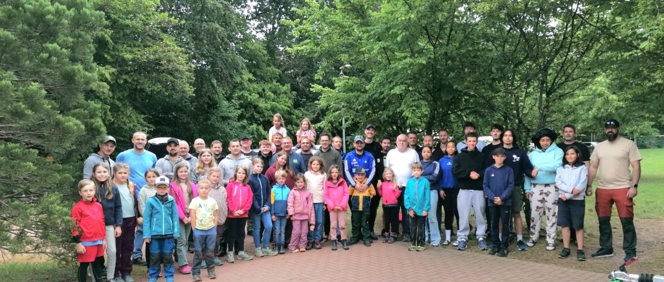 etwa 70 Kinder, Jugendliche, Väter und Großväter stehen im Halbkreis