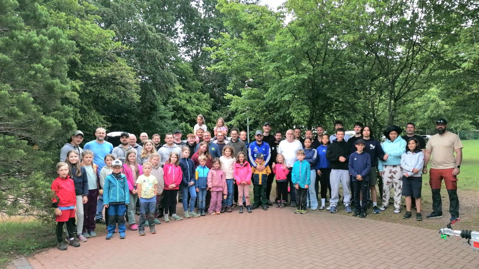 etwa 70 Kinder, Jugendliche, Väter und Großväter stehen im Halbkreis