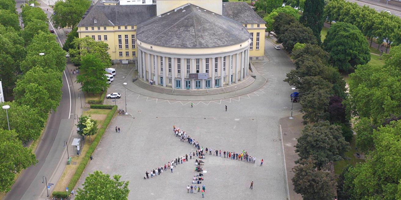 Ein Windrad aus Menschen auf einem Platz in Saarbrücken von oben fotografiert (c) Greenpeace; Karl-Carsten Steuer Ein Windrad aus Menschen auf einem Platz in Saarbrücken von oben fotografiert