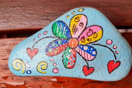 bemalter Stein mit bunter Blume und Herzen