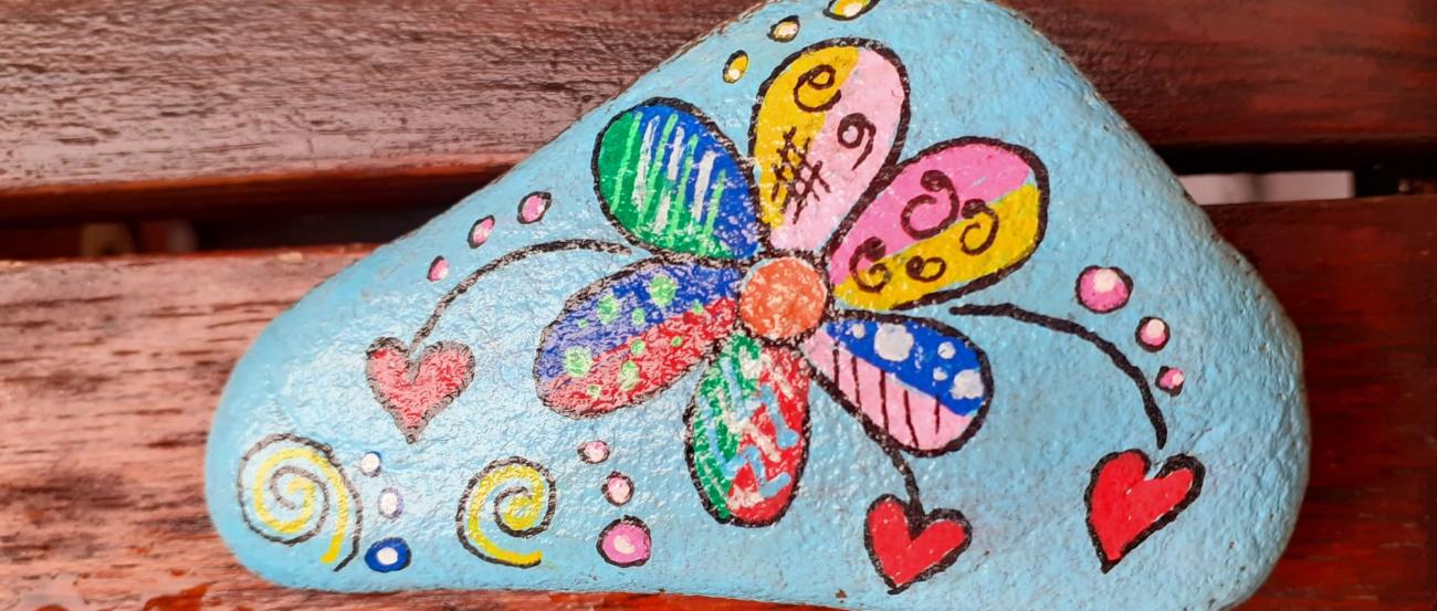 bemalter Stein mit bunter Blume und Herzen