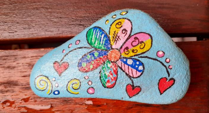 bemalter Stein mit bunter Blume und Herzen