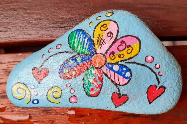 bemalter Stein mit bunter Blume und Herzen