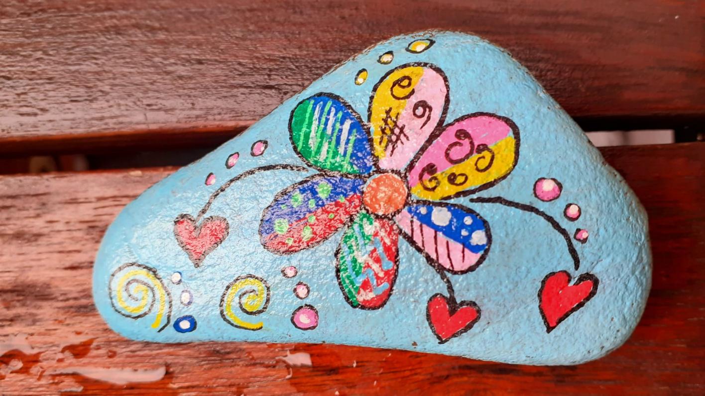 bemalter Stein mit bunter Blume und Herzen