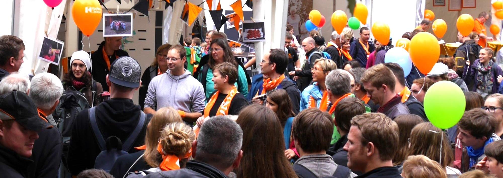 Man sieht eine Gruppe Menschen mit Kolpingschals und bunten Luftballons.