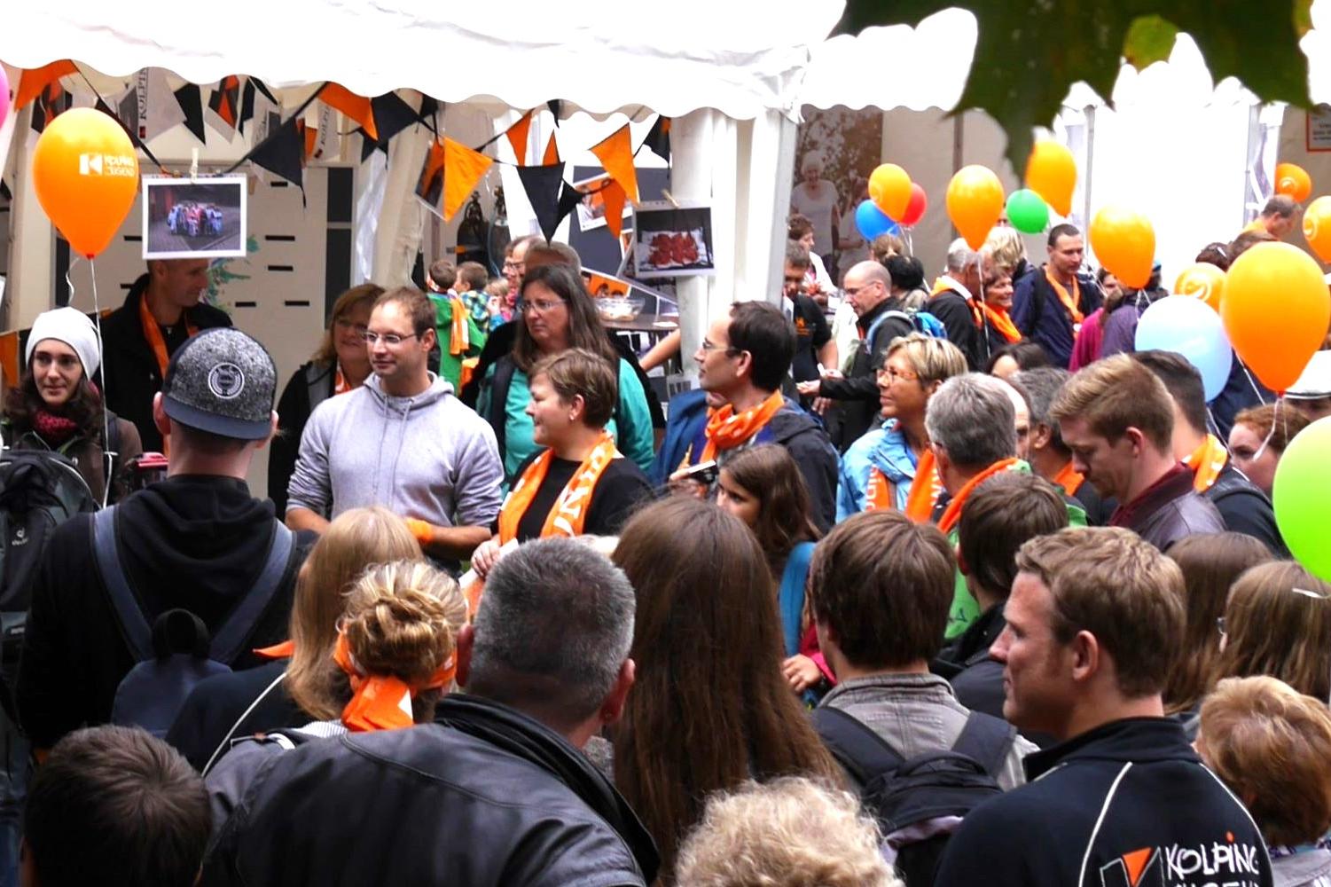 Man sieht eine Gruppe Menschen mit Kolpingschals und bunten Luftballons.