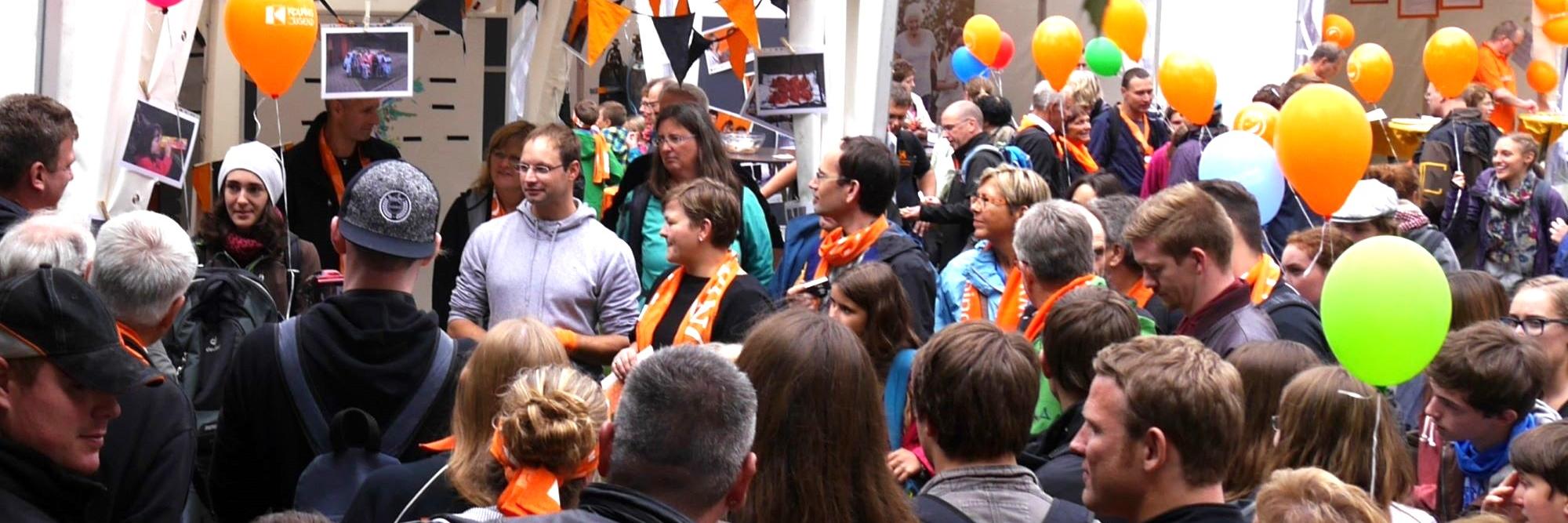 Man sieht eine Gruppe Menschen mit Kolpingschals und bunten Luftballons.