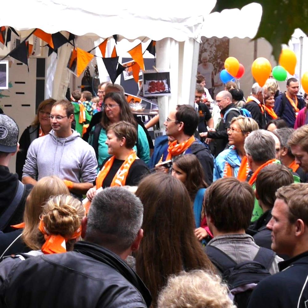 Man sieht eine Gruppe Menschen mit Kolpingschals und bunten Luftballons.