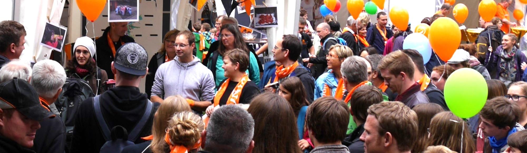 Man sieht eine Gruppe Menschen mit Kolpingschals und bunten Luftballons.