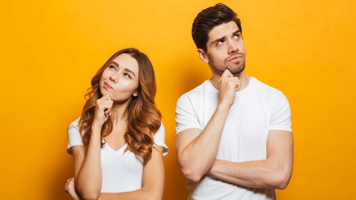 Zu sehen sind eine junge Frau und ein junger Mann in T-Shirts, die scheinbar nachdenken.