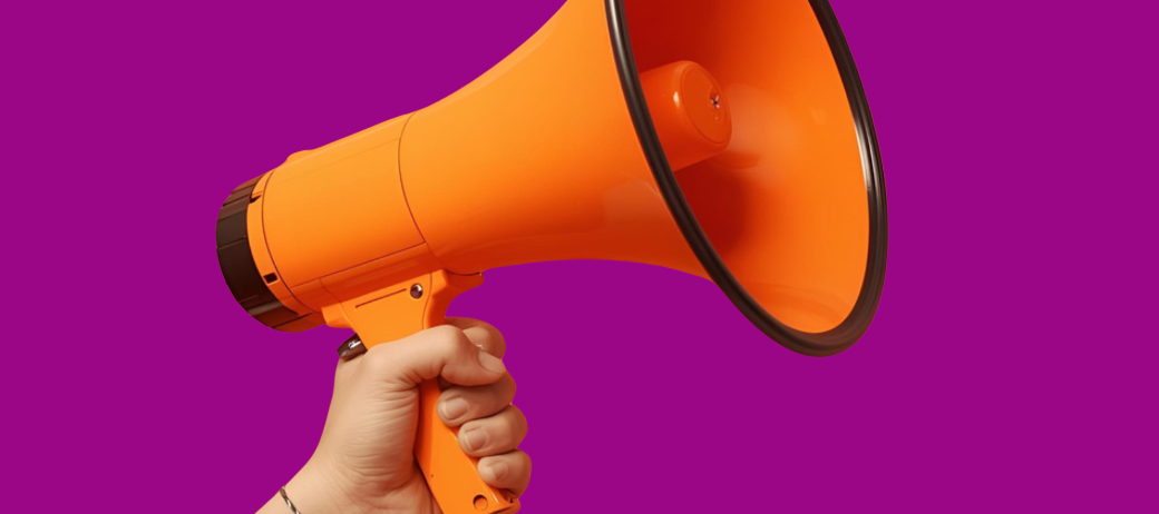 Hand, die ein oranges Megaphon hält vor purpurnem Hintergrund