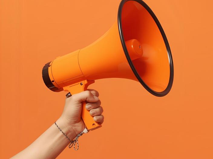 Hand, die ein orangenes Megaphon in der Hand hält