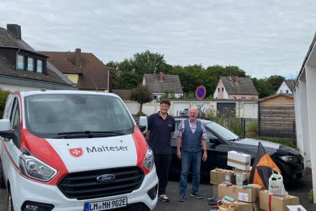 Ein Malteser Auto mit Malteser Mitarbeiter, dazu Werner Hammes und gesammelte Brillen