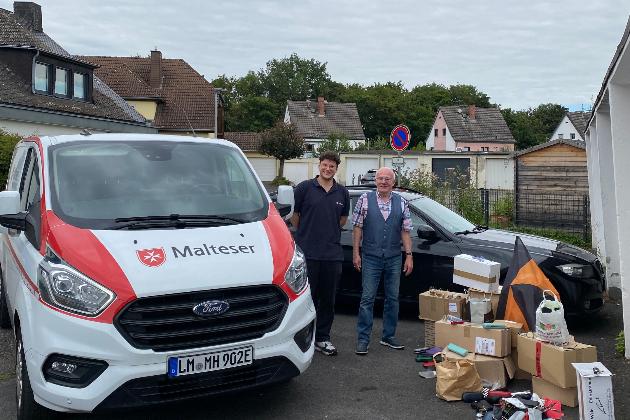 Ein Malteser Auto mit Malteser Mitarbeiter, dazu Werner Hammes und gesammelte Brillen