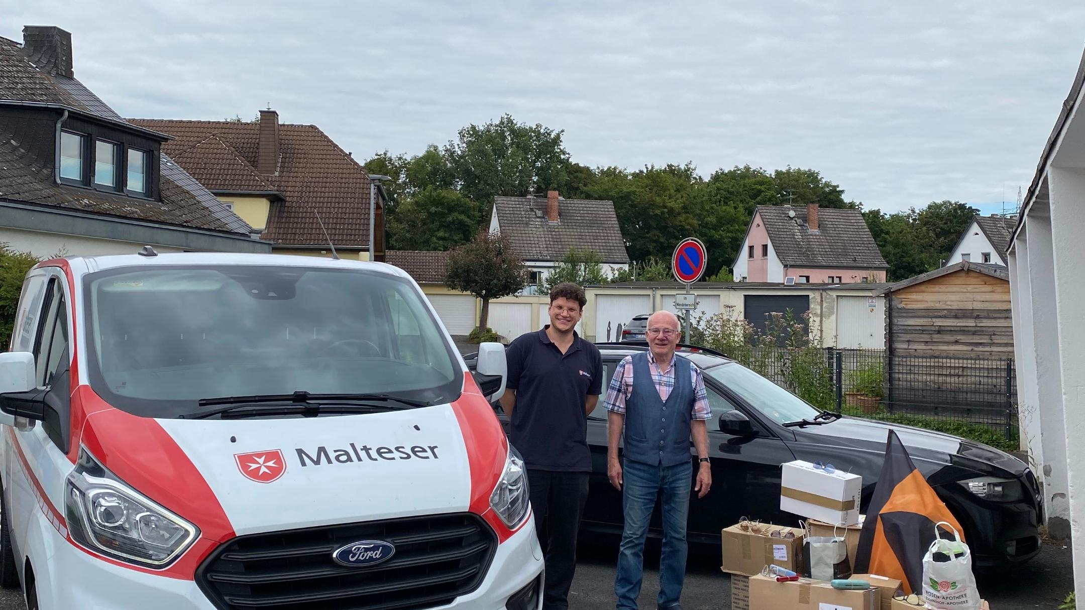 Ein Malteser Auto mit Malteser Mitarbeiter, dazu Werner Hammes und gesammelte Brillen
