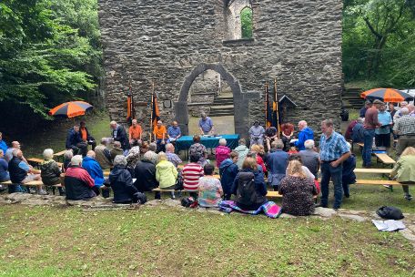 Menschen sitzen auf einer Wiese, im Hintergrund die Hausenborner Marienverehrungsstätte
