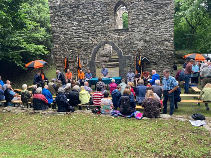 Menschen sitzen auf einer Wiese, im Hintergrund die Hausenborner Marienverehrungsstätte