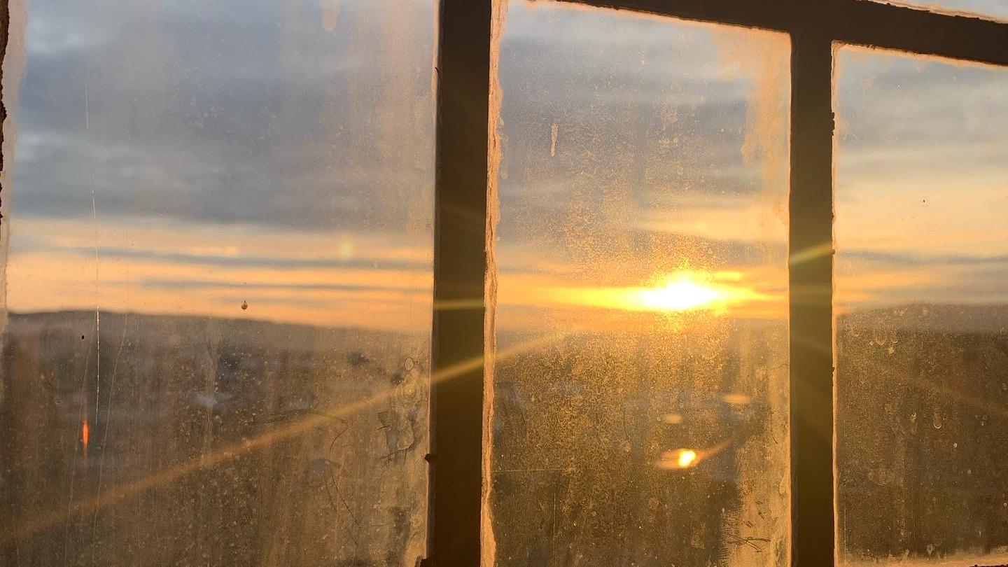 Blick durch ein Fenster auf einen Sonnenuntergang