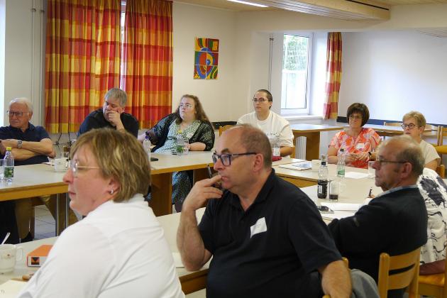 Menschen sitzen im Tagungsraum und hören einem Vortrag zu.