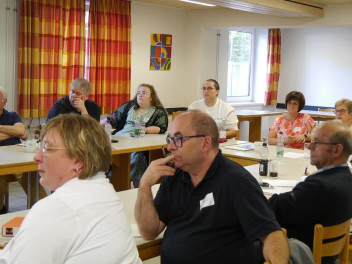 Menschen sitzen im Tagungsraum und hören einem Vortrag zu.