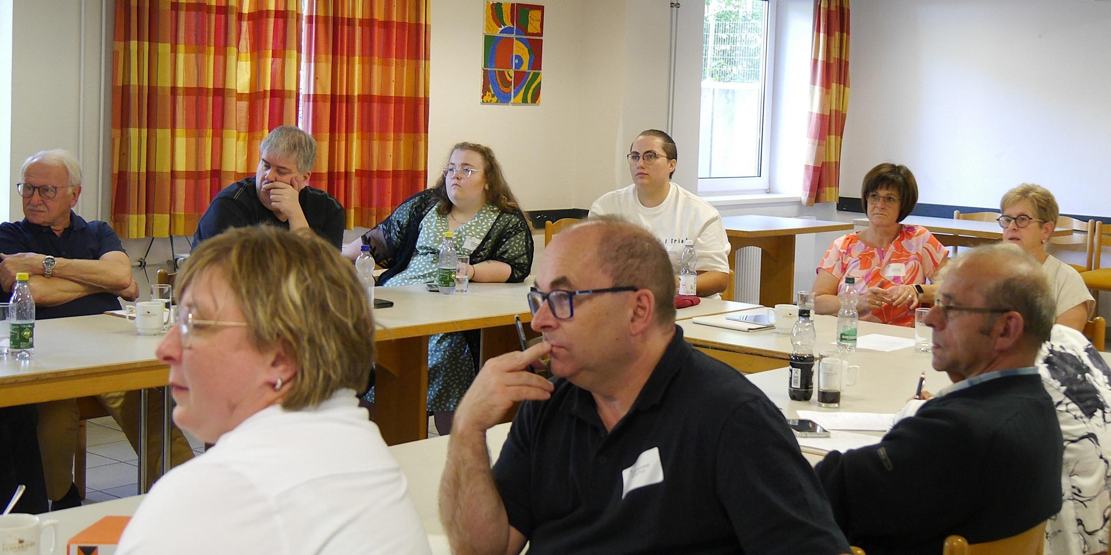 Menschen sitzen im Tagungsraum und hören einem Vortrag zu.