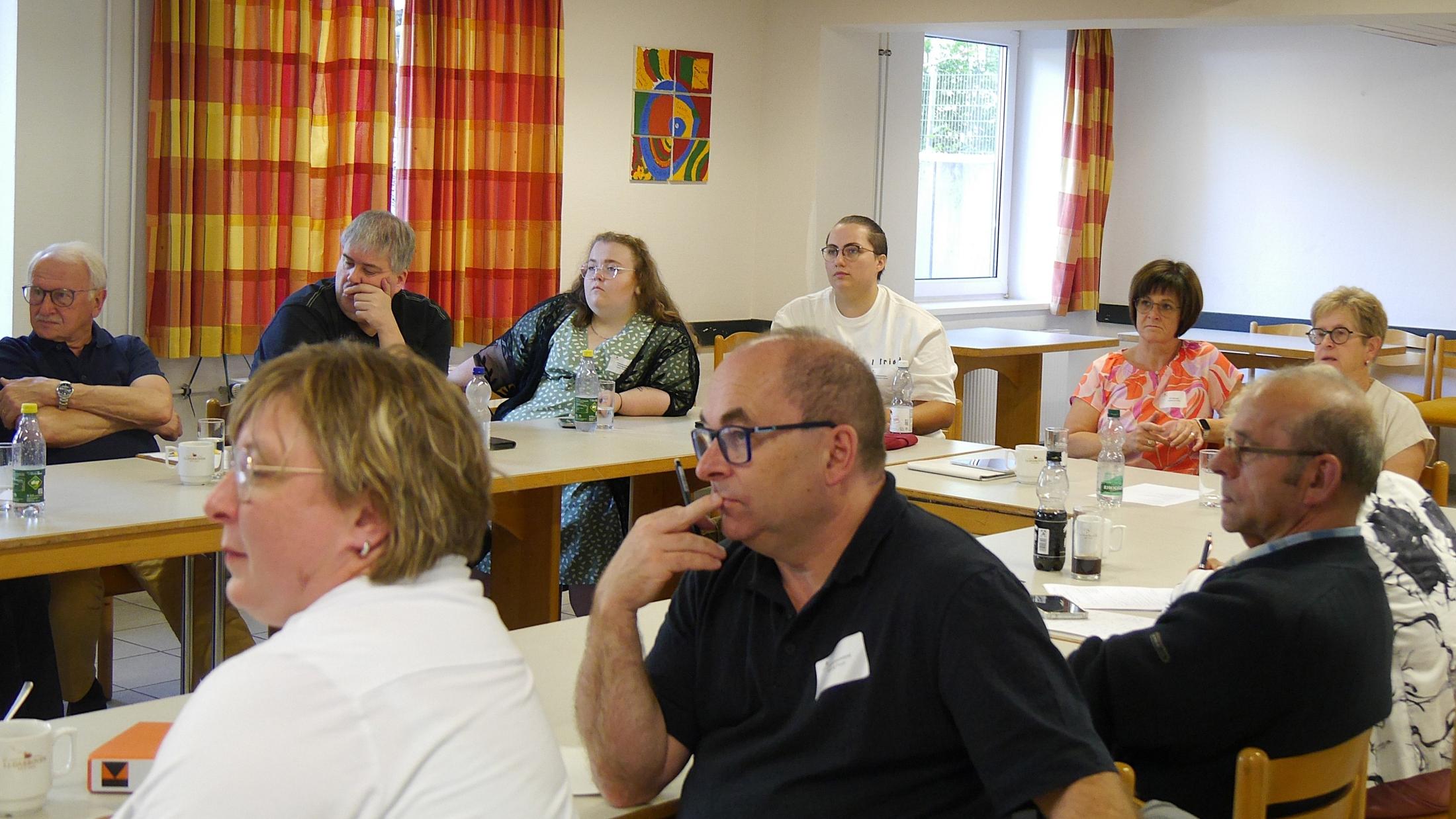 Menschen sitzen im Tagungsraum und hören einem Vortrag zu.