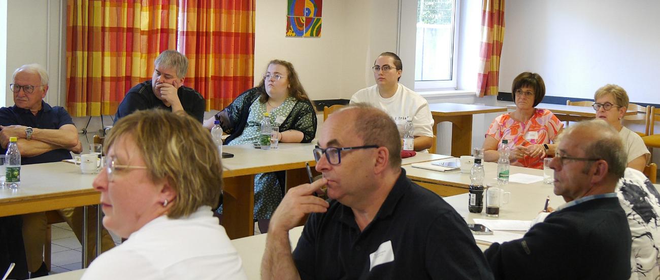 Menschen sitzen im Tagungsraum und hören einem Vortrag zu.