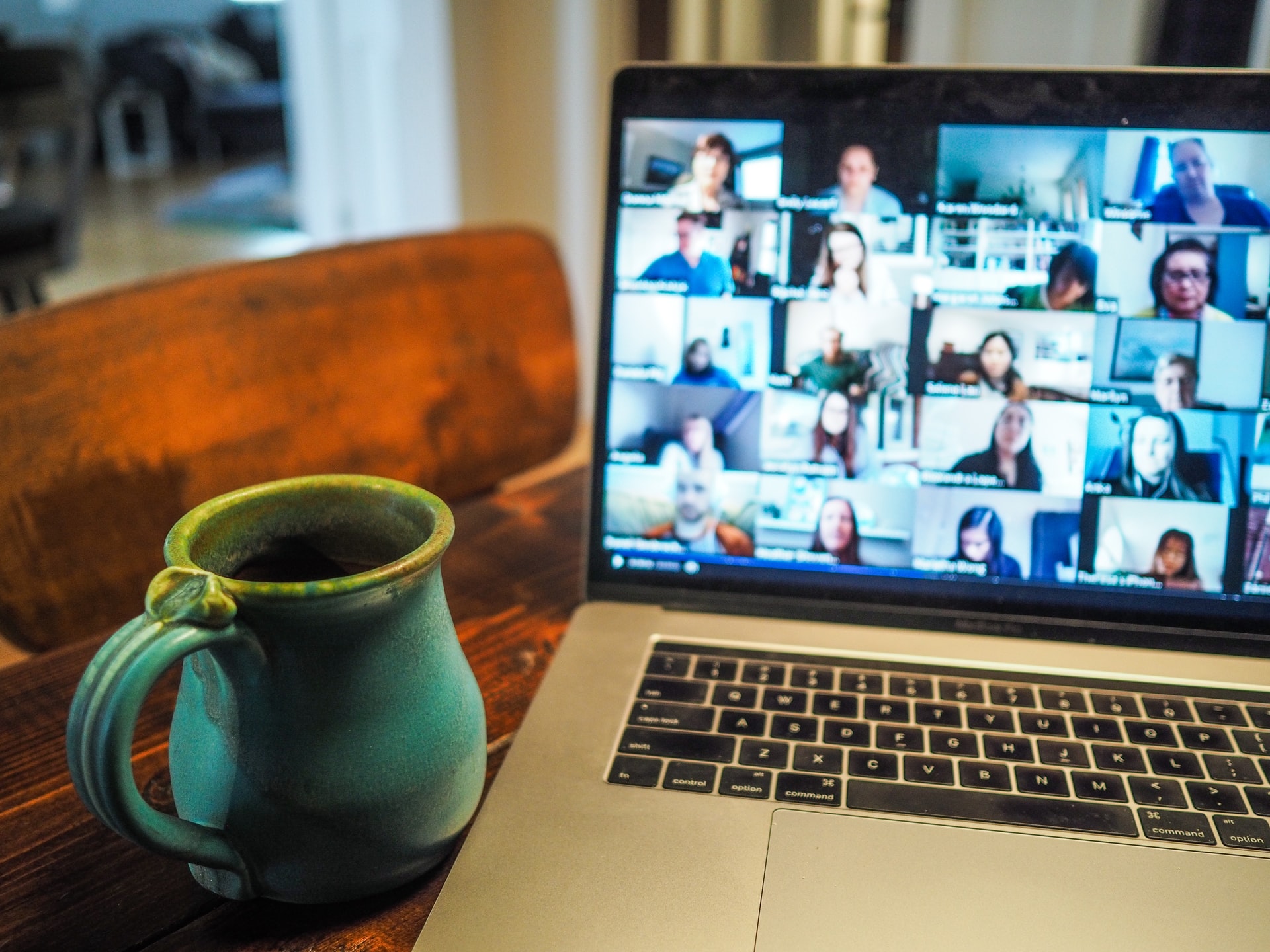 Laptop mit einer Videokonferenz; daneben auf dem Tisch eine Tasse