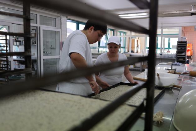 Ein Bäcker und eine Bäckerin bei der Arbeit in der Backstube