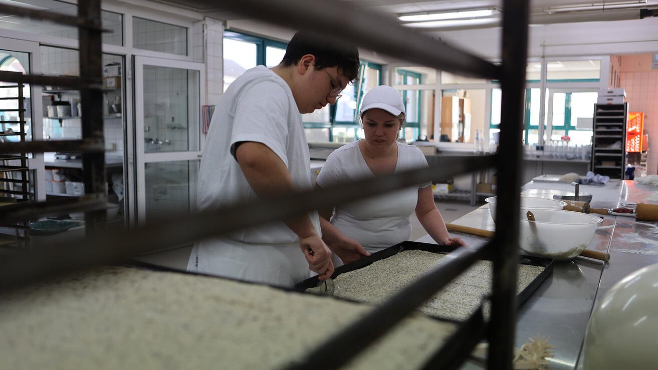 Ein Bäcker und eine Bäckerin bei der Arbeit in der Backstube
