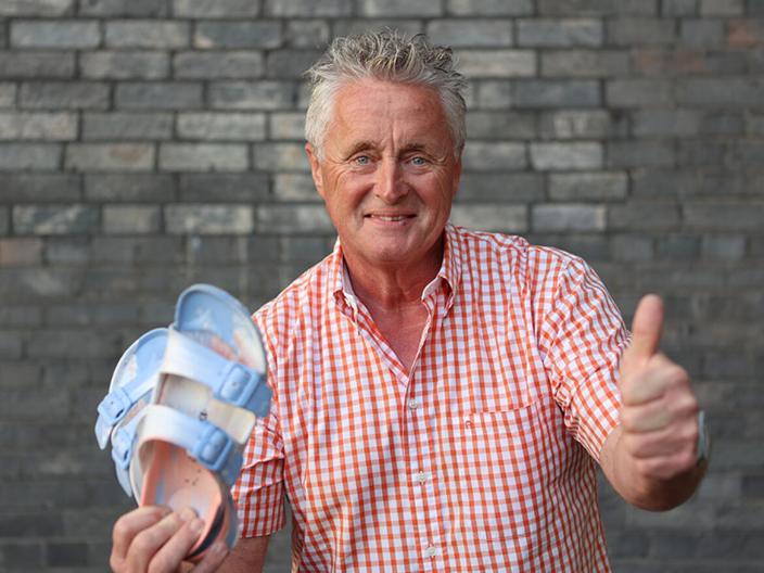Otto Jacobs hält in der einen Hand ein Paar Schuhe und reckt den linken Daumen hoch.