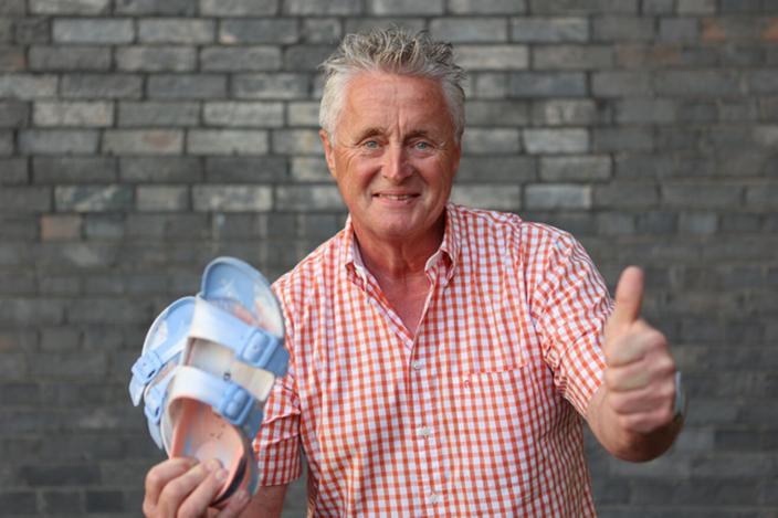 Otto Jacobs hält in der einen Hand ein Paar Schuhe und reckt den linken Daumen hoch.