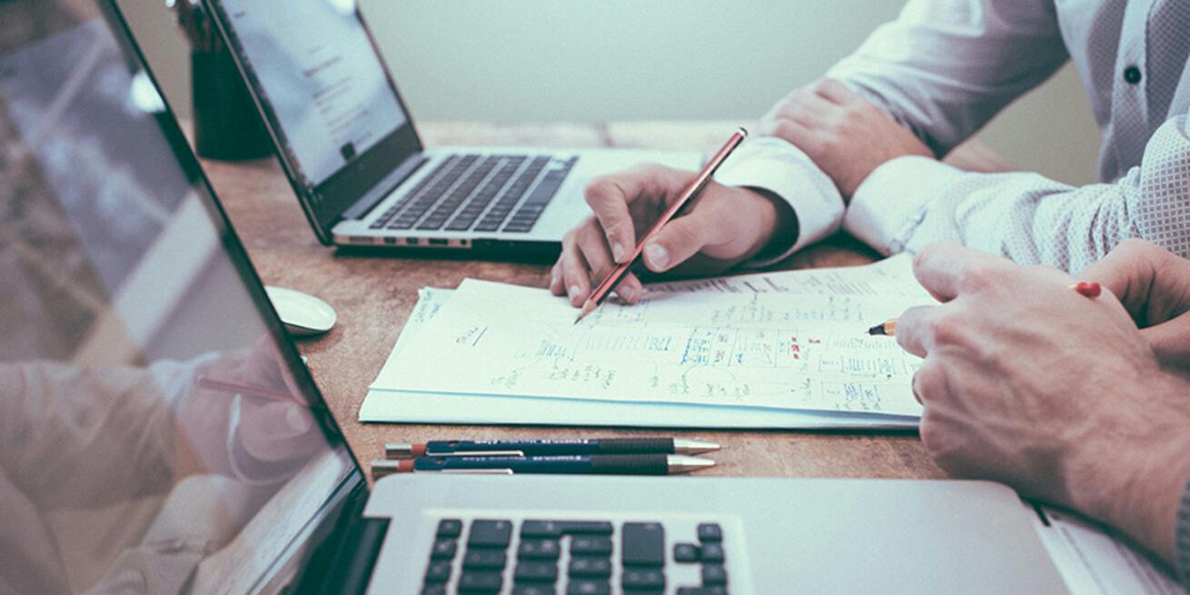 zwei Laptops, dazwischen Versicherungsunterlagen mit Daten und Zahlen und die Arme von zwei Personen (c) Scott_Graham_Unsplash_96f02f47b1 zwei Laptops, dazwischen Versicherungsunterlagen mit Daten und Zahlen und die Arme von zwei Personen