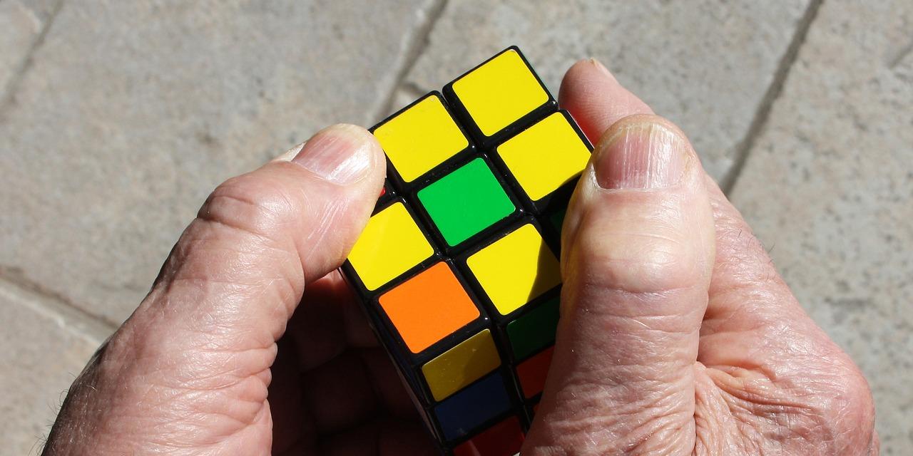 Man sieht zwei alte Hände, die einen Zauberwürfel halten.