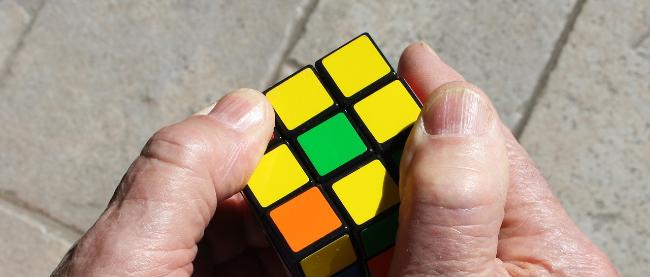 Man sieht zwei alte Hände, die einen Zauberwürfel halten.